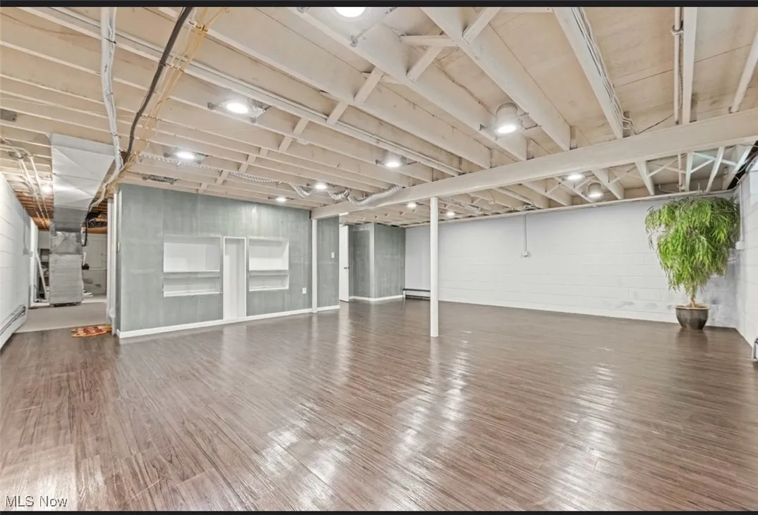 Unfinished basement featuring concrete block wall and dark wood-type flooring