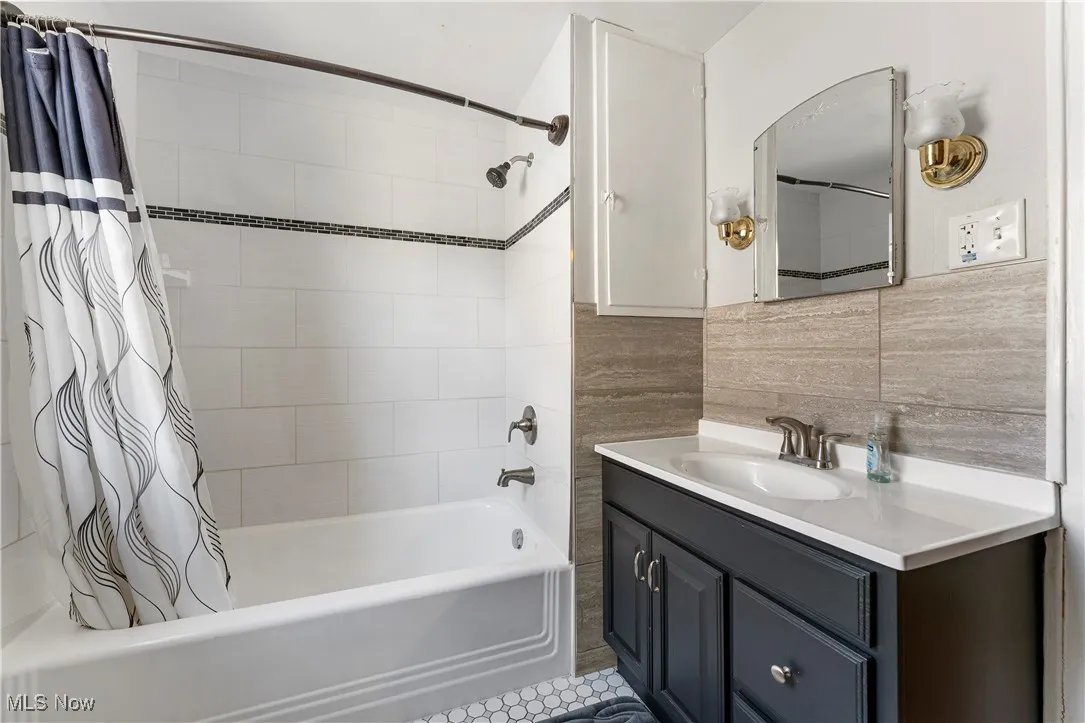 Full bathroom with shower / bathtub combination with curtain, tile walls, vanity, and light tile patterned floors