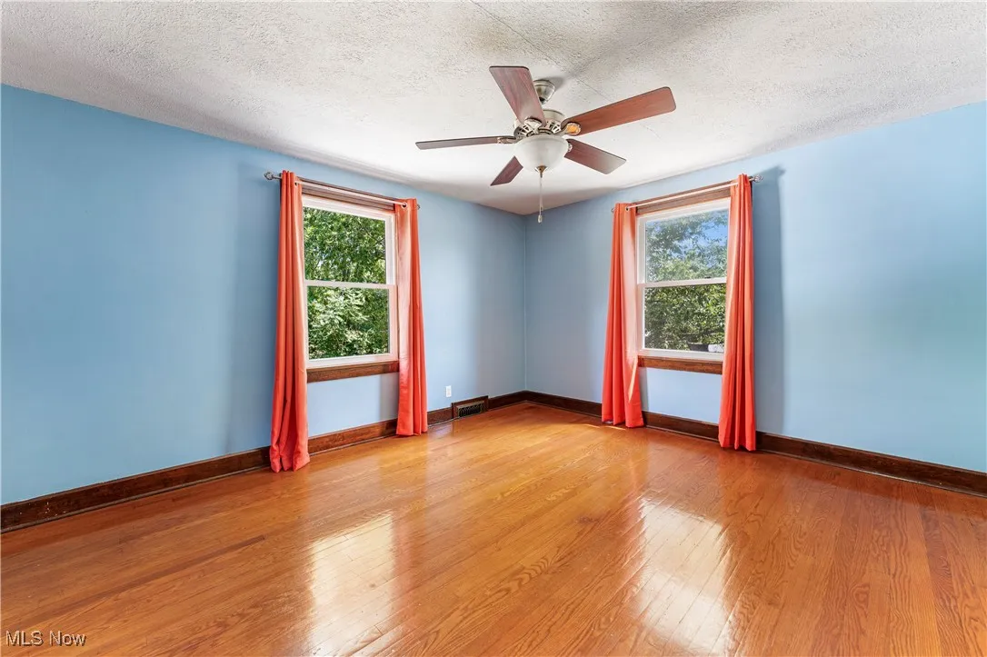 Unfurnished room with light wood finished floors, plenty of natural light, a textured ceiling, and a ceiling fan