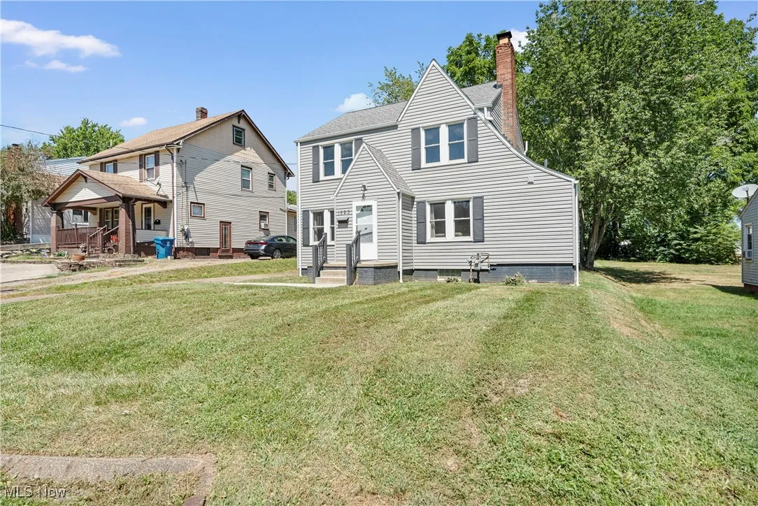 Rear view of house with a chimney and a yard