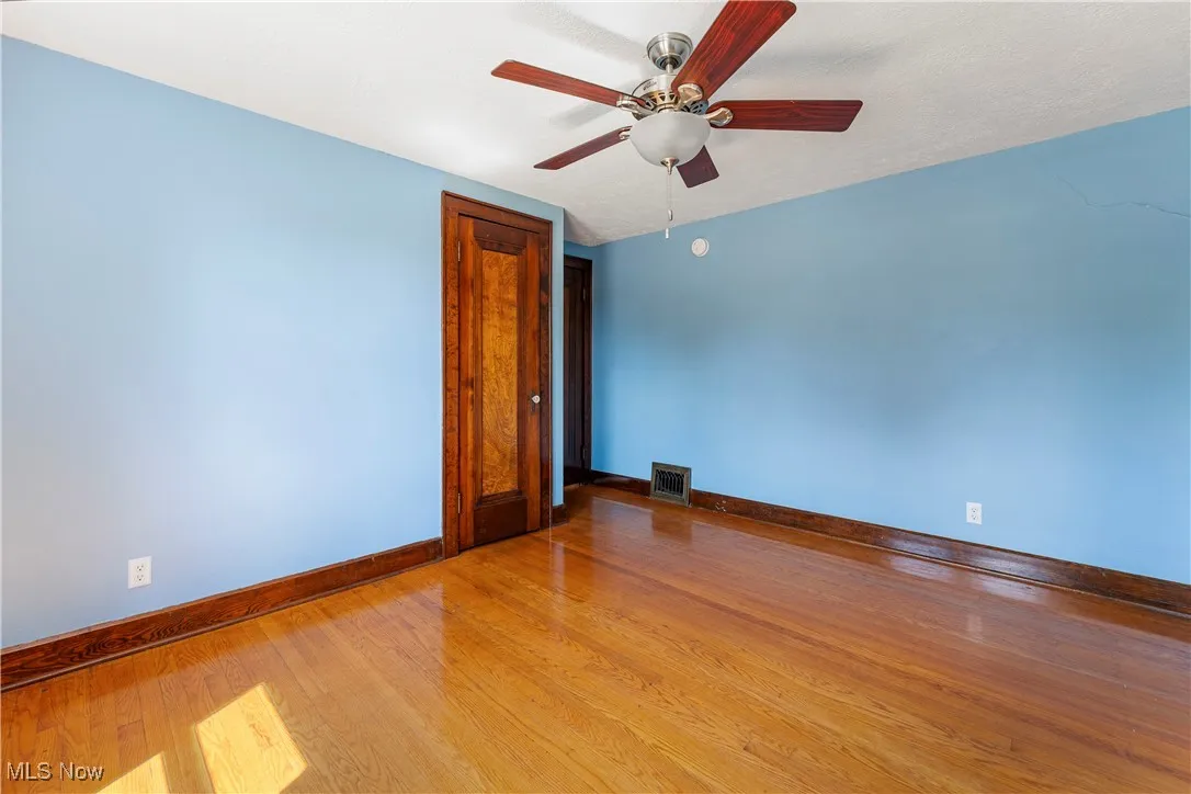 Empty room with wood finished floors and ceiling fan