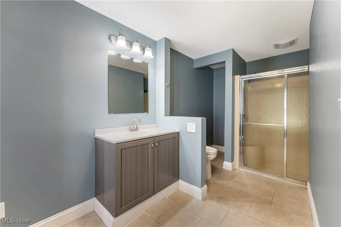 Full bathroom with vanity, a stall shower, and light tile patterned floors