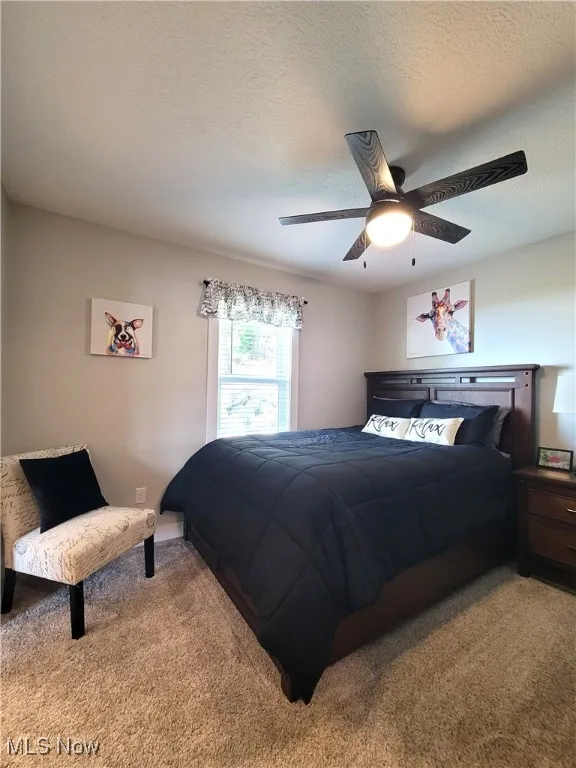 Carpeted bedroom with a textured ceiling and ceiling fan