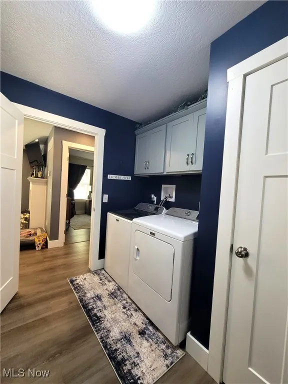 Laundry area with dark wood-style flooring, a textured ceiling, cabinet space, and independent washer and dryer