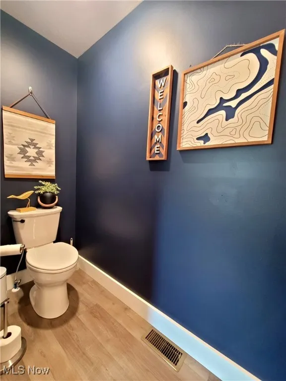 Half bath with wood finished floors and baseboards