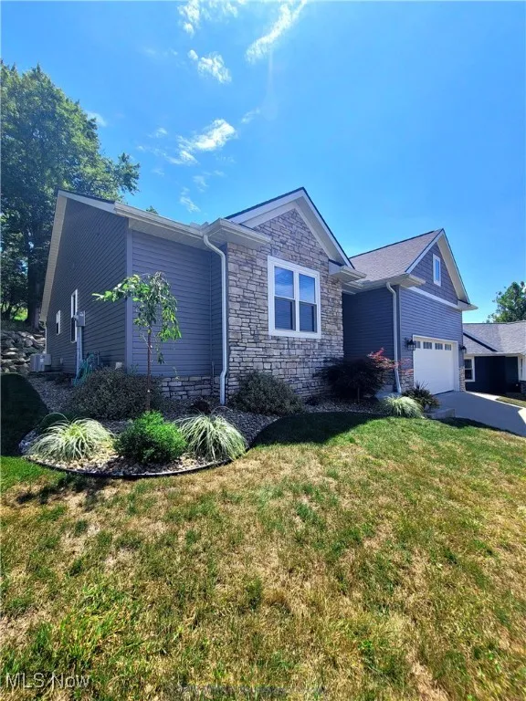 Single story home with stone siding, a front yard, and an attached garage