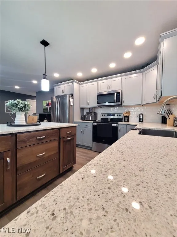 Kitchen featuring appliances with stainless steel finishes, pendant lighting, recessed lighting, backsplash, and light countertops