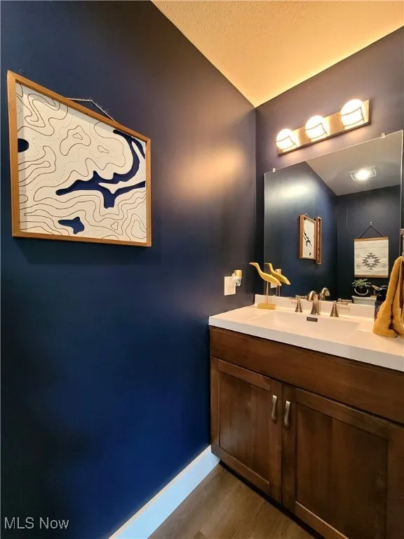 Half bath with vanity, dark wood-style floors, and a textured ceiling