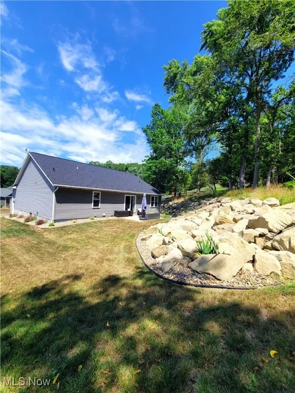 Back of house featuring a patio and a yard with stone wall