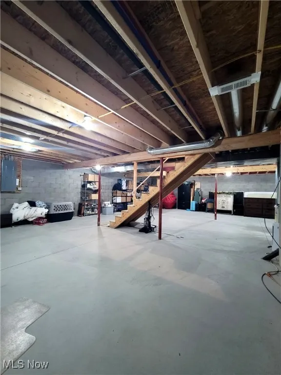 Unfinished basement with stairway and electric panel