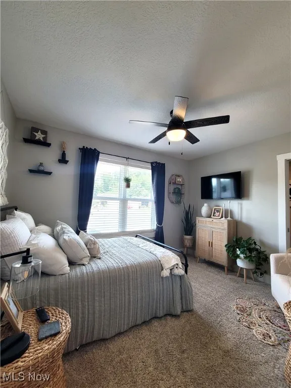 Carpeted bedroom with a textured ceiling and ceiling fan