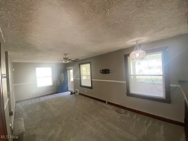Spare room featuring carpet flooring, a textured ceiling, and ceiling fan