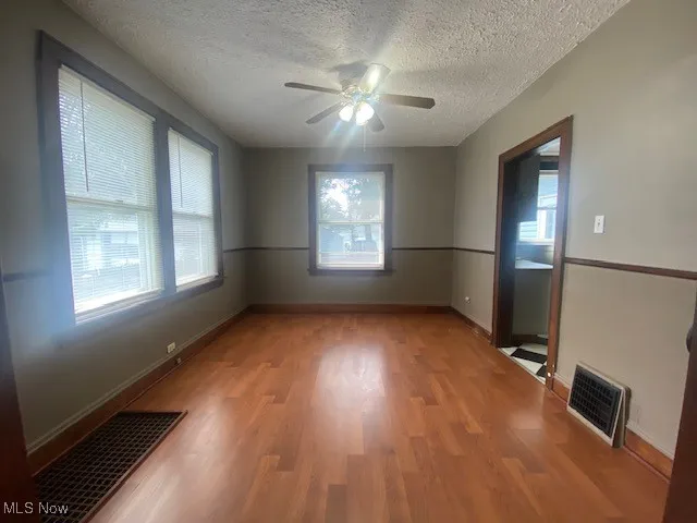 Unfurnished room featuring plenty of natural light, light wood-style flooring, a textured ceiling, and ceiling fan