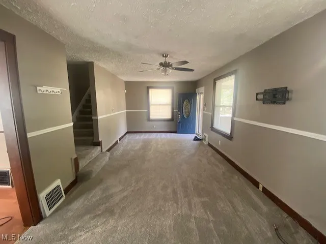 Corridor featuring carpet flooring, a textured ceiling, and stairway