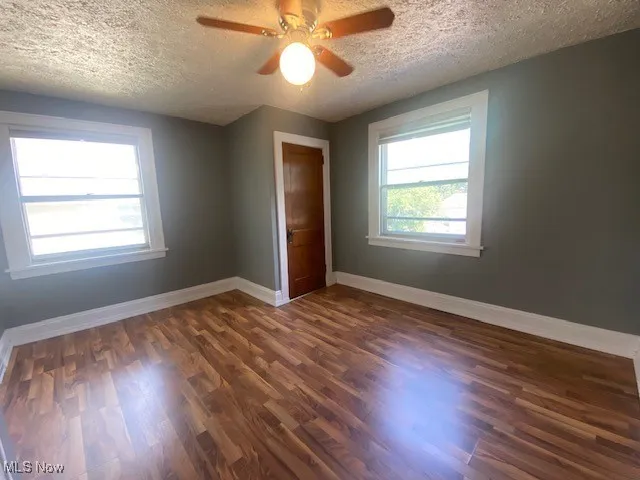 Unfurnished room with dark wood-type flooring, a textured ceiling, and ceiling fan