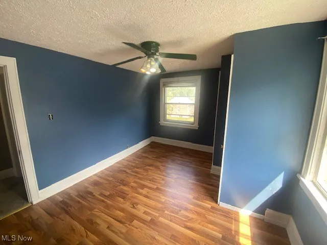 Unfurnished bedroom featuring wood finished floors, a textured ceiling, and a ceiling fan