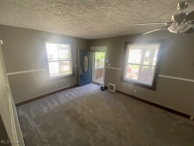Carpeted entryway with a textured ceiling and ceiling fan