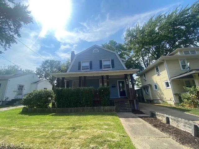 Dutch colonial featuring a gambrel roof, a porch, a front yard, and a chimney