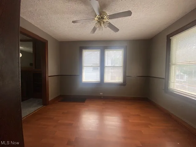 Unfurnished room featuring wood finished floors, a textured ceiling, and a ceiling fan