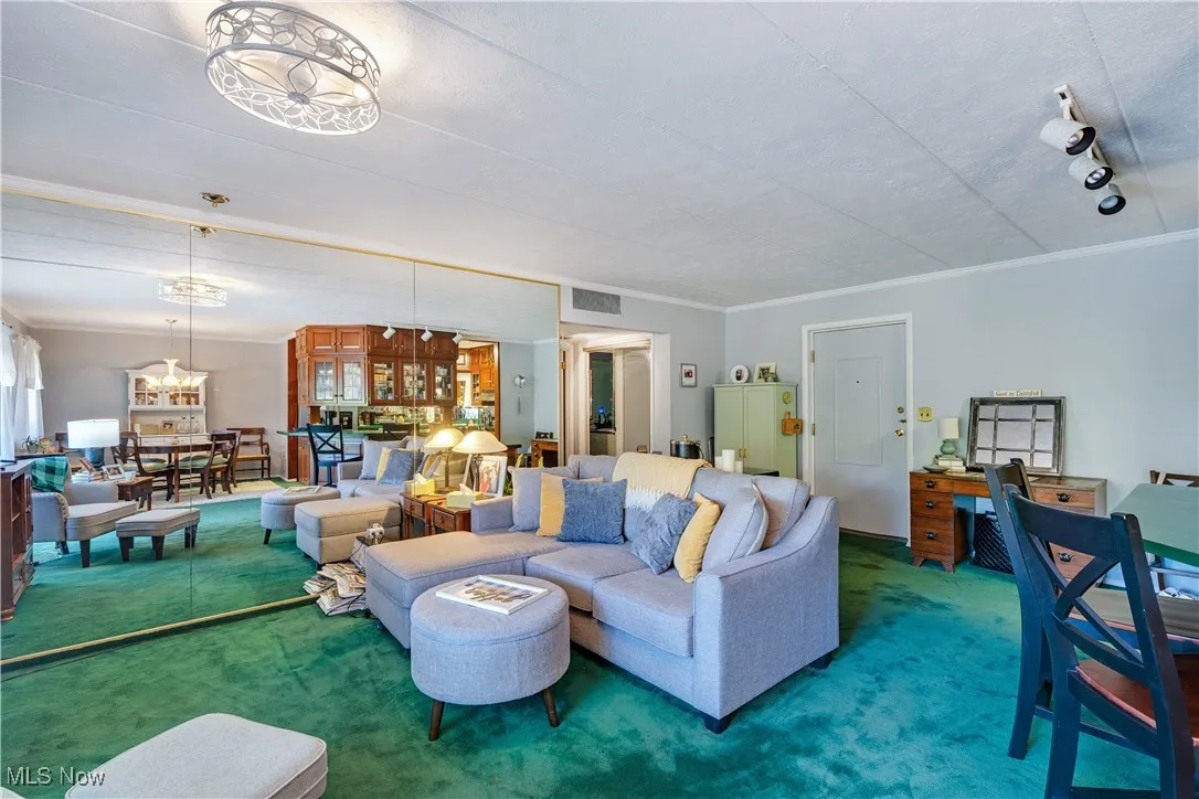 Living area featuring crown molding, carpet flooring, a chandelier, and a desk