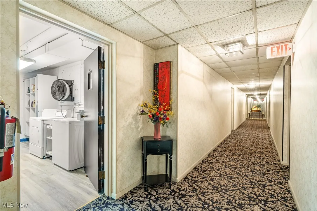 Hall featuring a paneled ceiling and stacked washer / drying machine