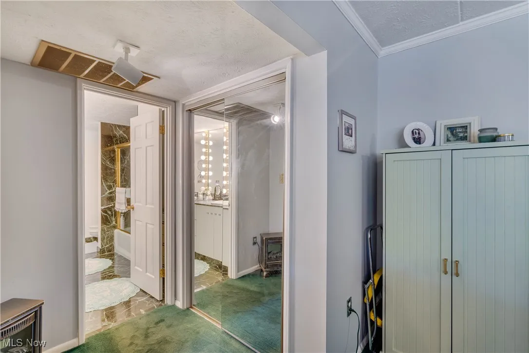 Hallway featuring a textured ceiling, carpet, and crown molding