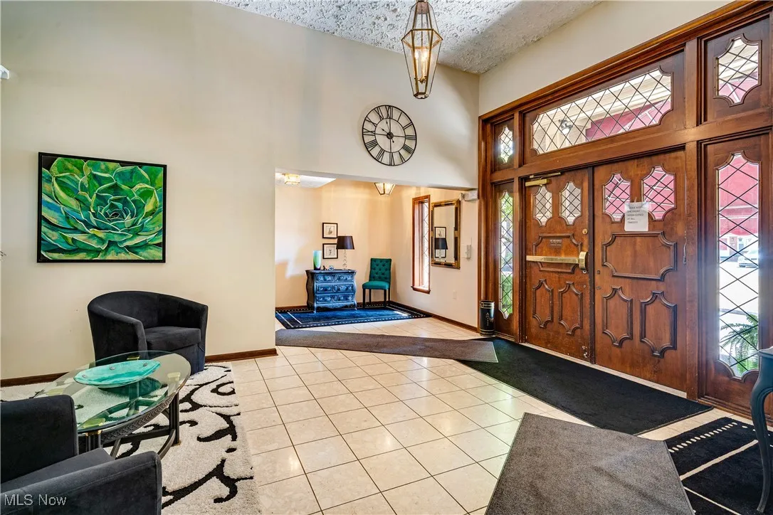 Foyer with light tile patterned flooring, a towering ceiling, and a textured ceiling