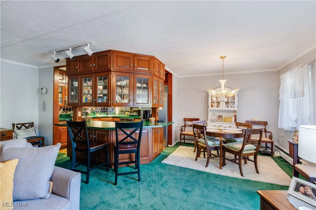 Dining area featuring ornamental molding, carpet flooring, a chandelier, a textured ceiling, and rail lighting