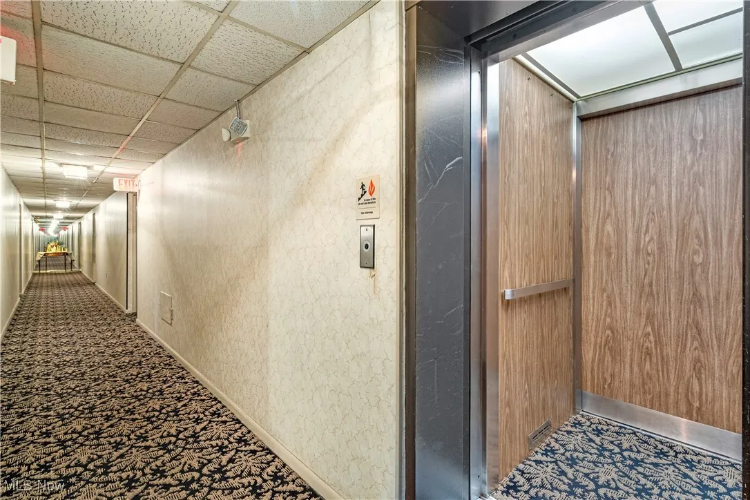 Hallway with elevator and a paneled ceiling