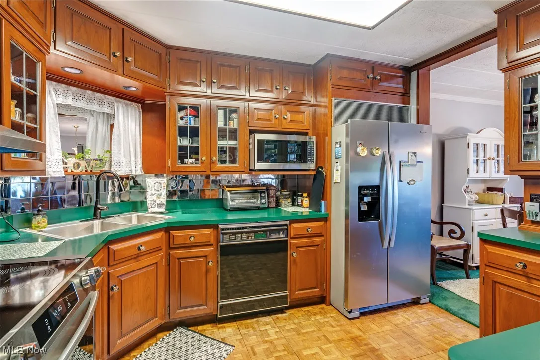 Kitchen with glass insert cabinets, stainless steel appliances, brown cabinets, and crown molding