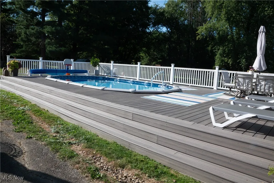 View of pool with a deck and view of scattered trees