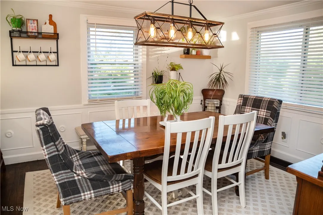 Dining room with a decorative wall, wainscoting, crown molding, plenty of natural light, and wood finished floors