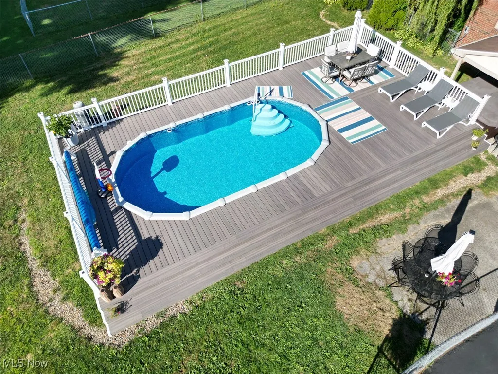 View of pool with outdoor dining space, a deck, and a lawn