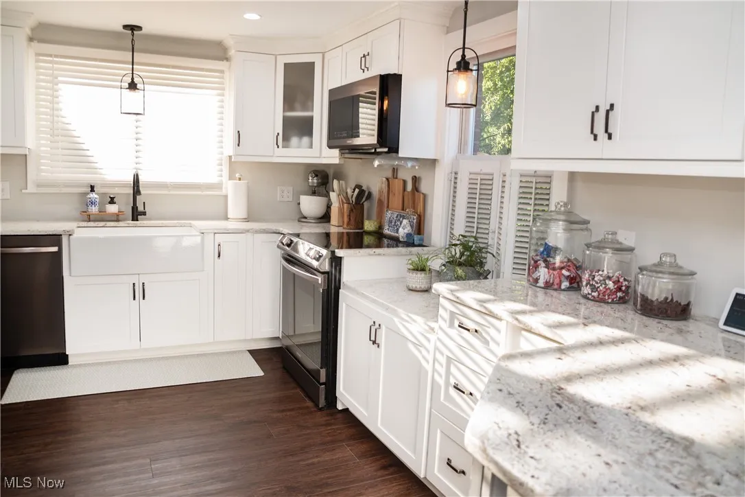 Kitchen featuring decorative light fixtures, white cabinets, appliances with stainless steel finishes, light stone counters, and recessed lighting