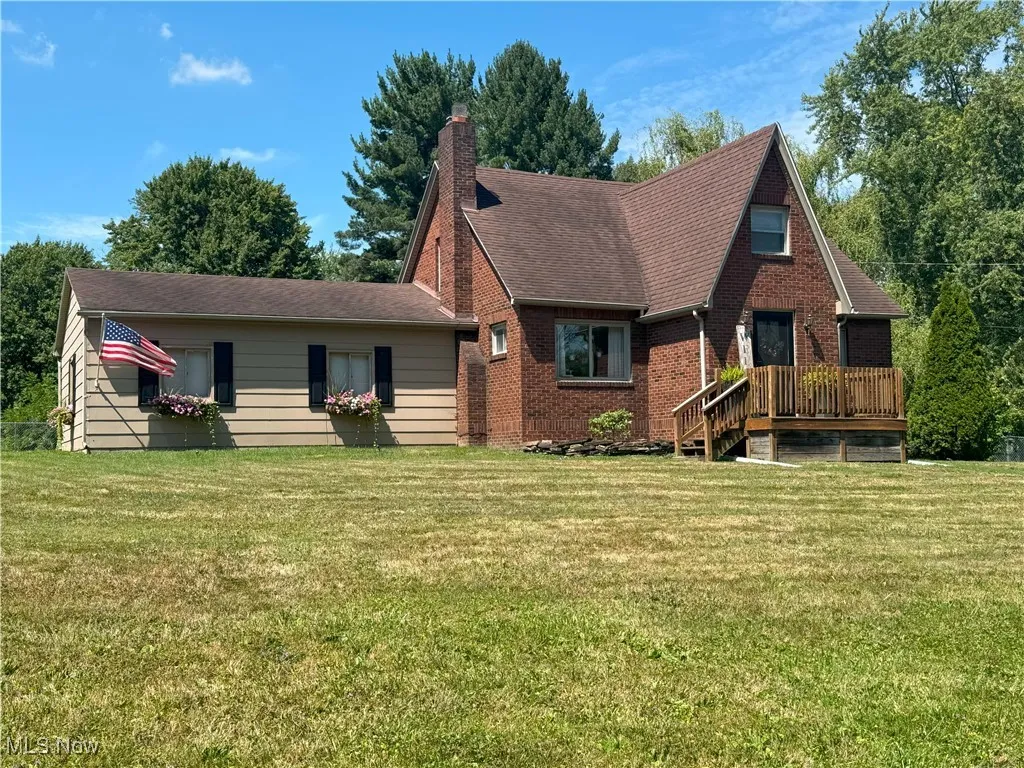 Front view of house with a lawn, a chimney, brick siding, and a shingled roof