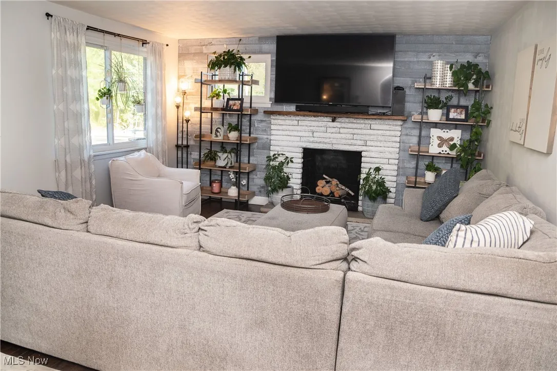 Living area with a fireplace, wooden walls, and wood finished floors
