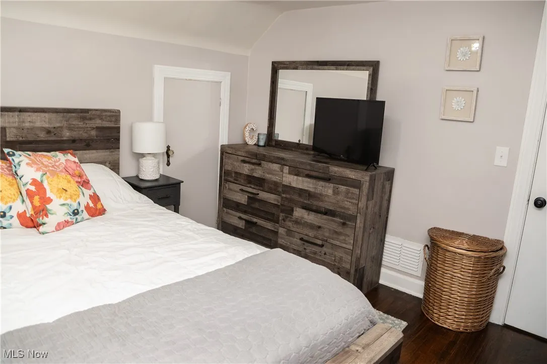 Bedroom featuring dark wood-type flooring and vaulted ceiling