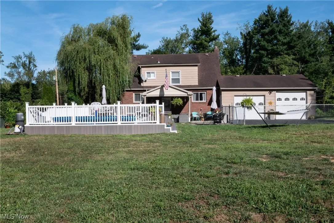 Rear view of house with a deck, brick siding, and an attached garage