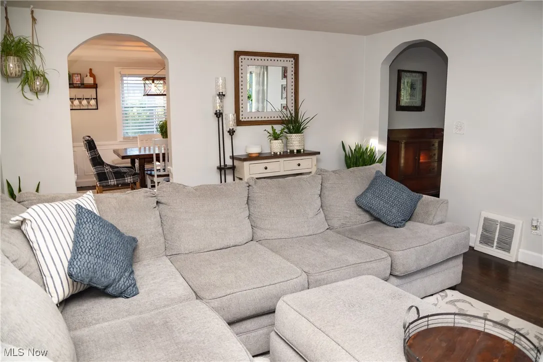 Living area featuring arched walkways and wood finished floors