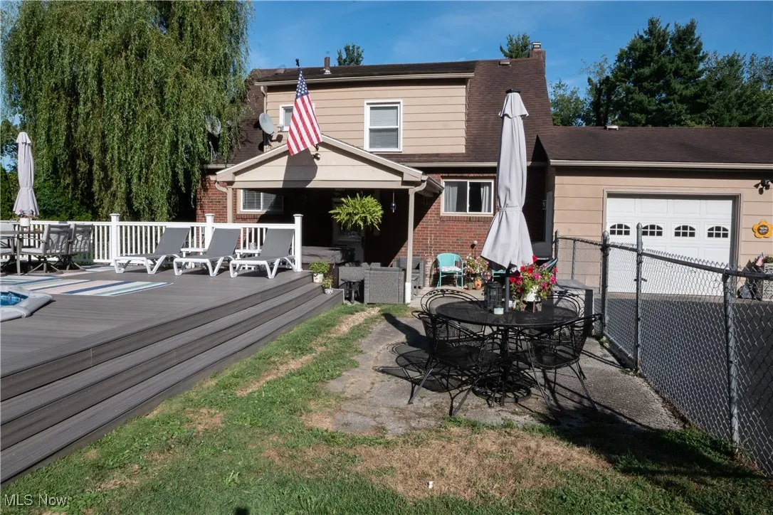 Back of property with outdoor dining area, a garage, a deck, a patio area, and brick siding