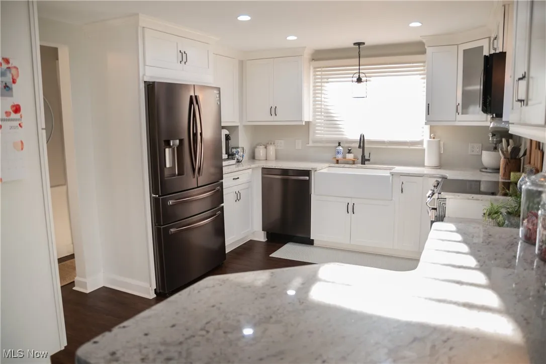Kitchen with light stone counters, stainless steel appliances, white cabinetry, pendant lighting, and recessed lighting