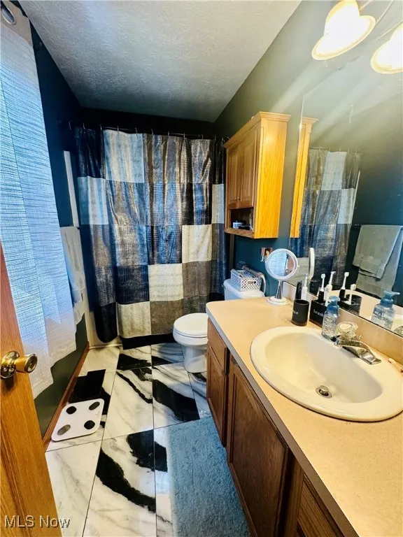 Bathroom featuring vanity, a textured ceiling, and a shower with shower curtain