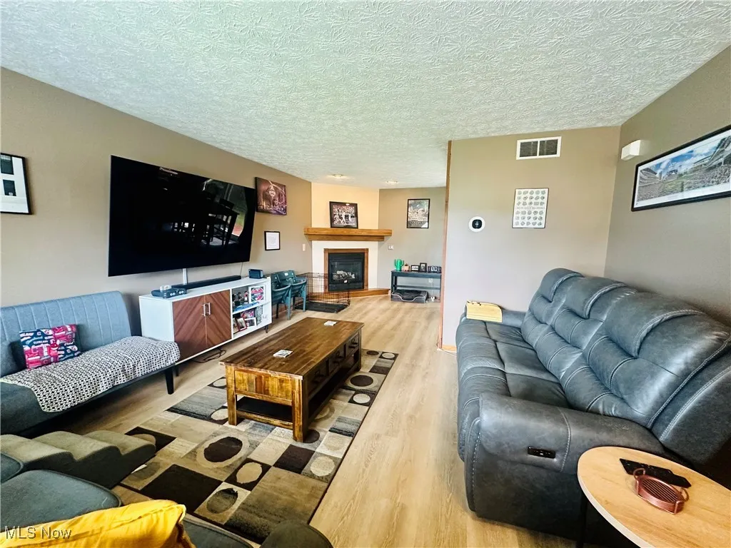 Living area featuring wood finished floors, a fireplace, and a textured ceiling