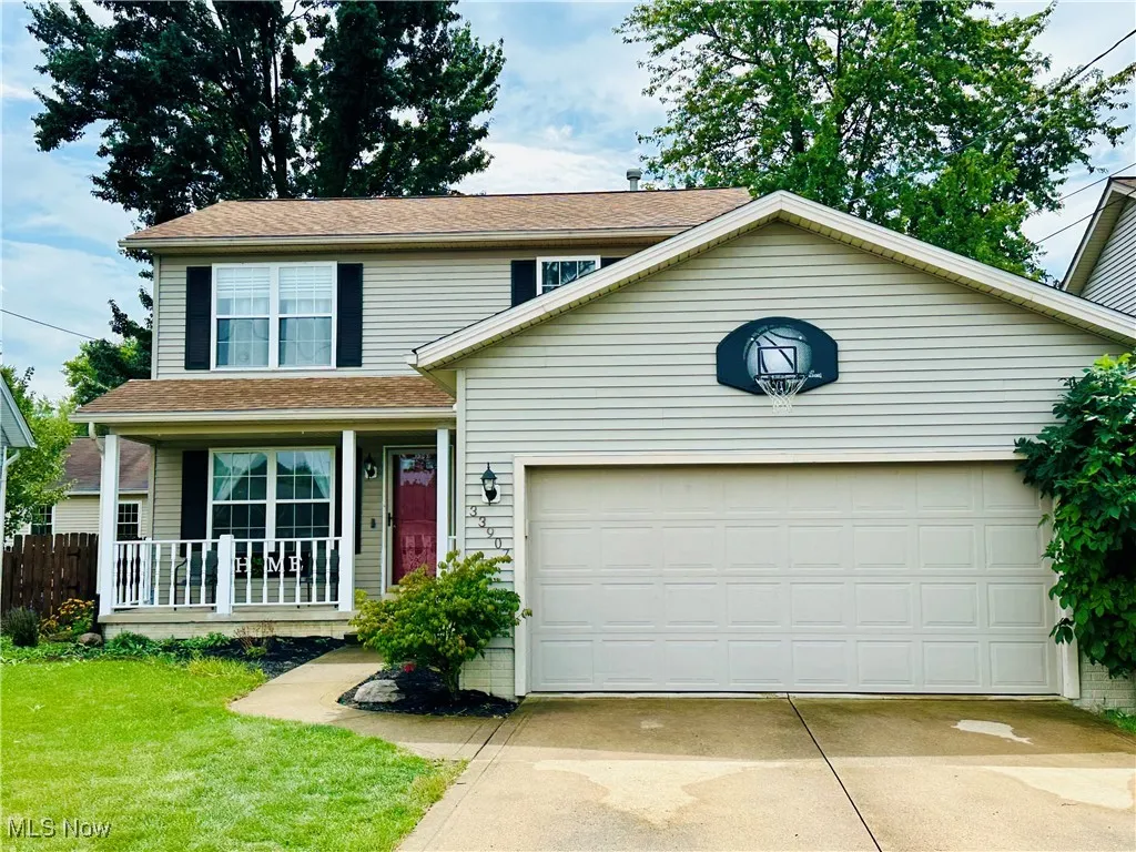 Traditional-style home with concrete driveway, a garage, a porch, and a shingled roof