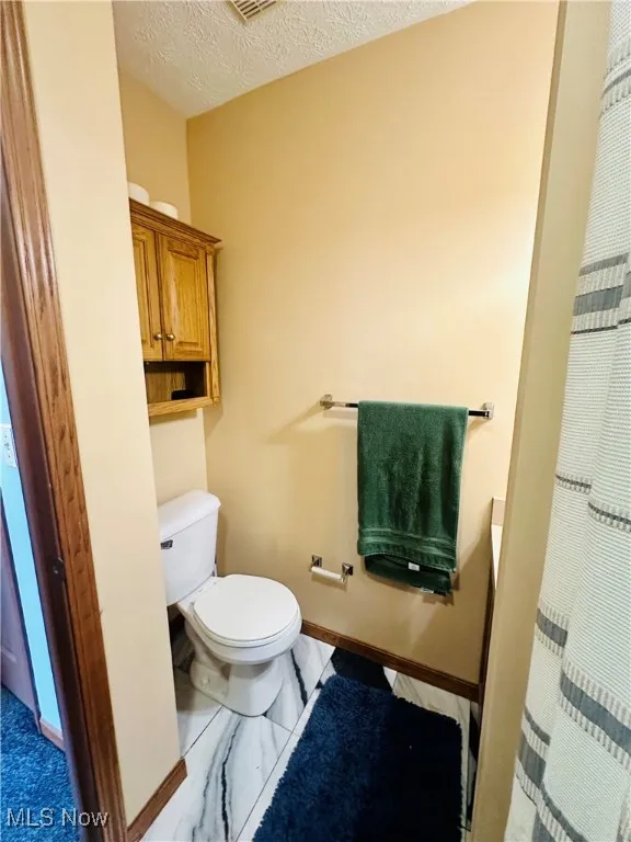 Full bathroom with a textured ceiling and a shower with curtain