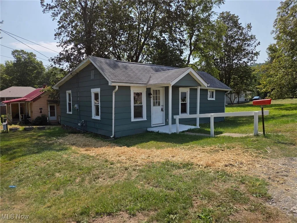 View of front of home featuring a front lawn and a shingled roof