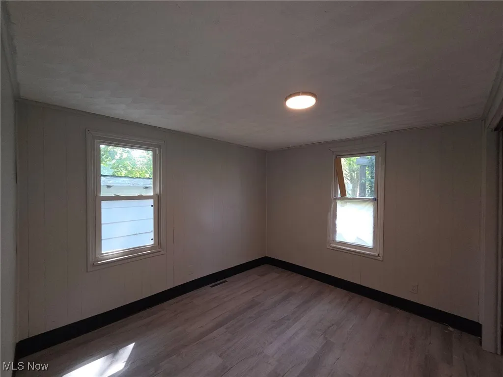 Empty room featuring dark wood-style flooring and wood walls