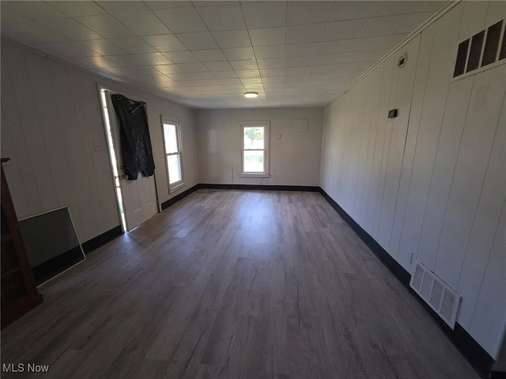 Unfurnished living room with dark wood-type flooring and wooden walls