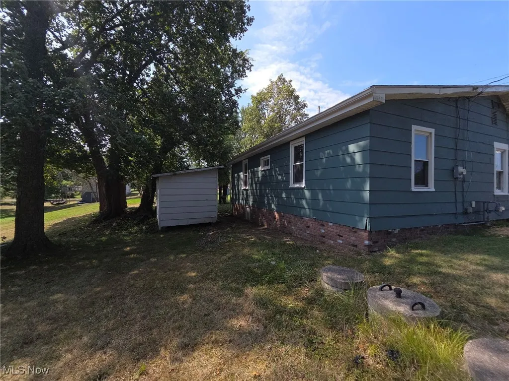 View of home's exterior with crawl space and a yard