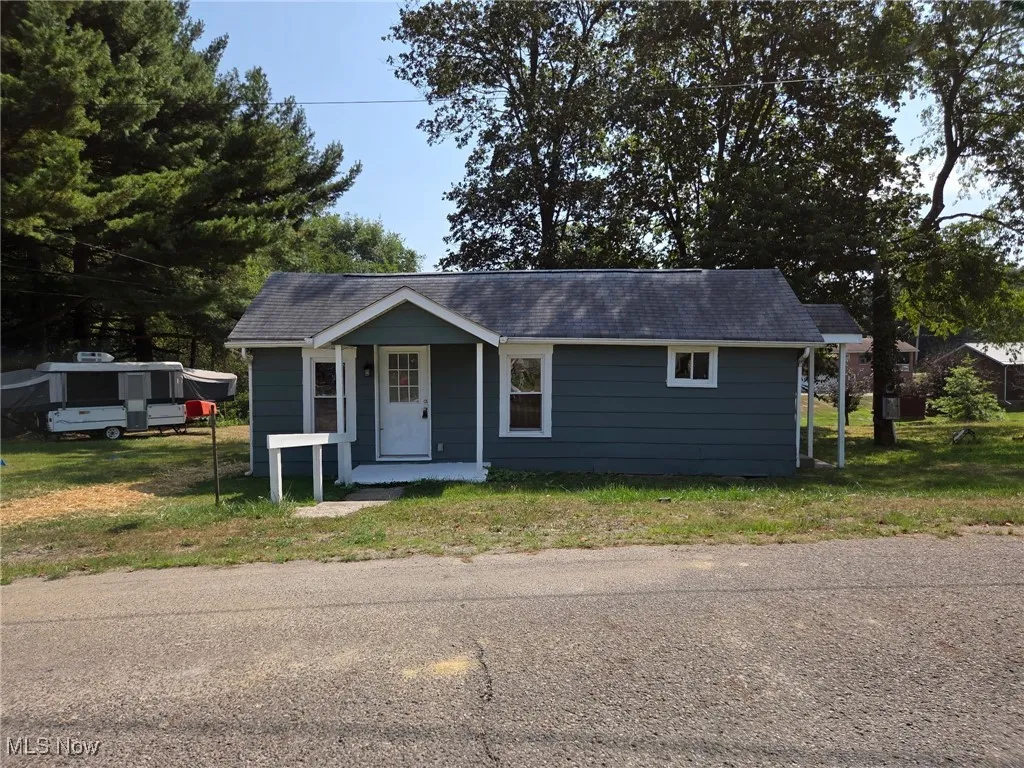 View of front of home featuring a front yard, roof with shingles, and a porch